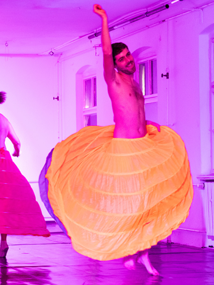 Performer*innen tanzen in bunten Röcken