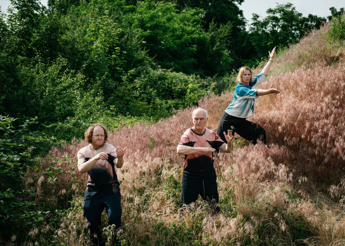 Three people are standing in tall grass